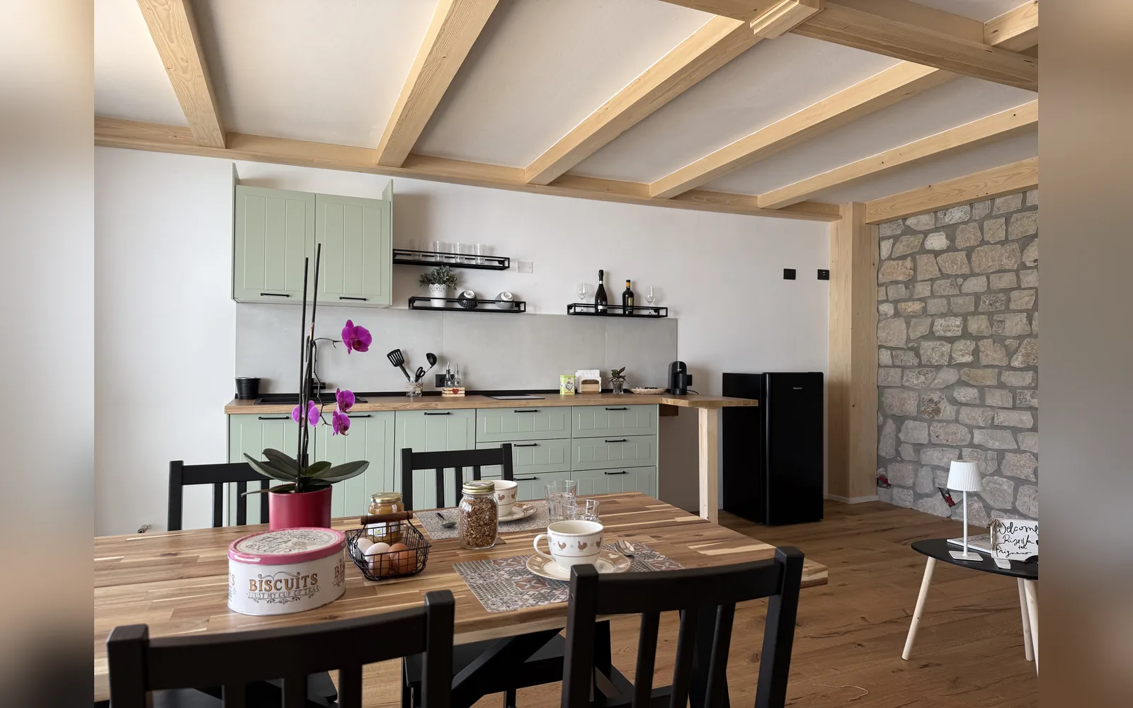 Die Küche des Studios mit gedecktem Holztisch und Steinwand