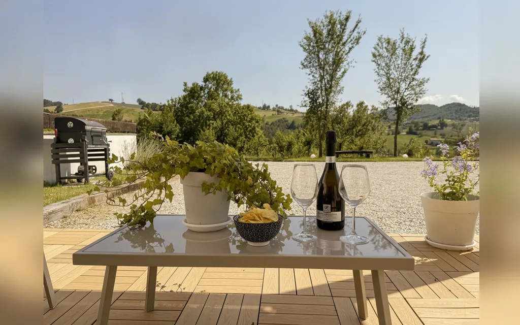Der gedeckte Terrassentisch mit Gläsern und Flasche, vor den Hügeln