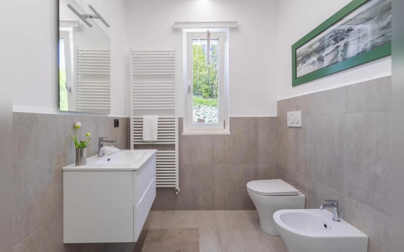 Das Bad der Erdgeschosswohnung mit Waschtisch, Bidet und Fenster zum Garten