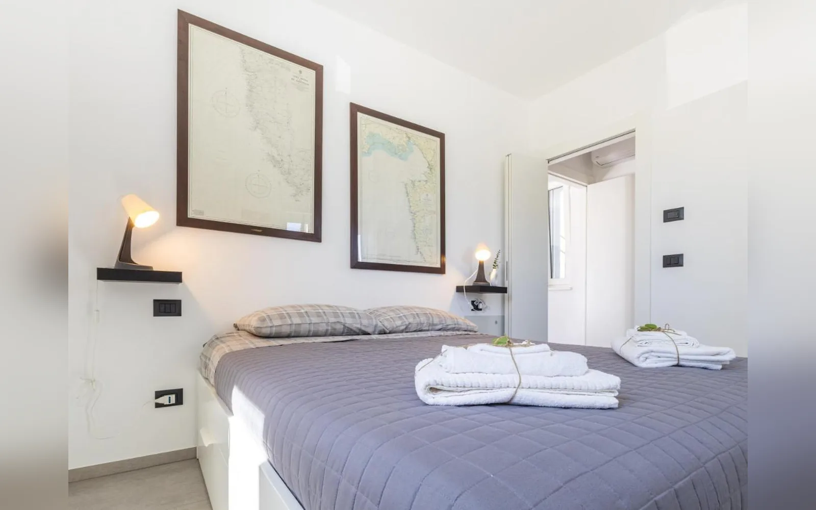 Das Doppelschlafzimmer der Erdgeschosswohnung, mit gerahmten Drucken und bereitgelegten Handtüchern