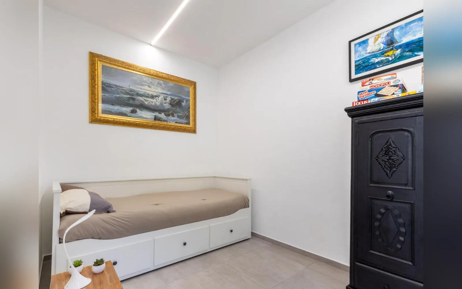 Das zweite Schlafzimmer der Erdgeschosswohnung, mit verwandelbarem Einzelbett und geschnitztem antiken Schrank